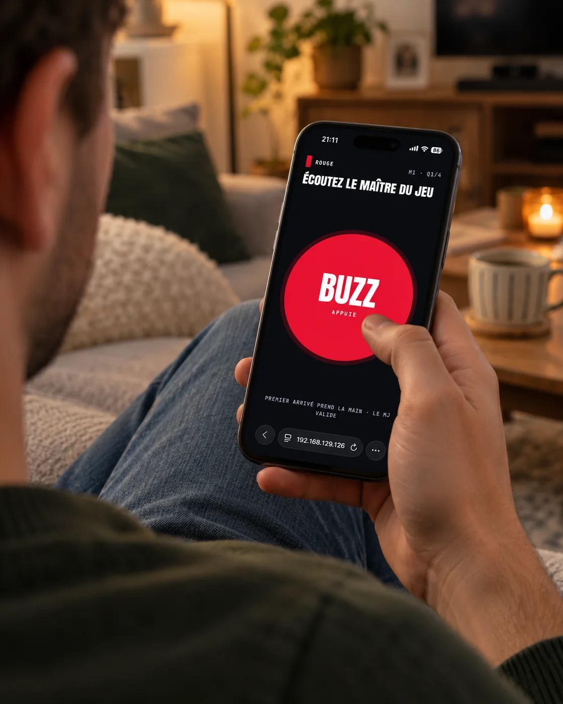 An illustrative mockup of a person on a sofa holding a phone with the game’s large red BUZZ button, thumb ready to press.